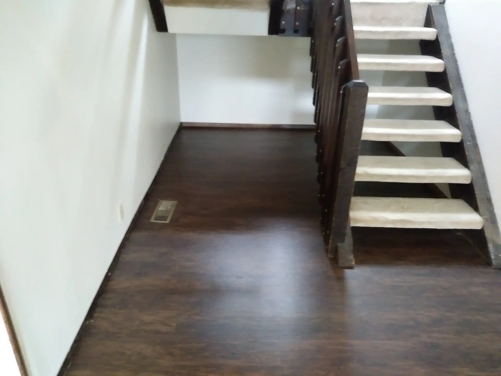 Dark laminate flooring in a hallway beside a staircase