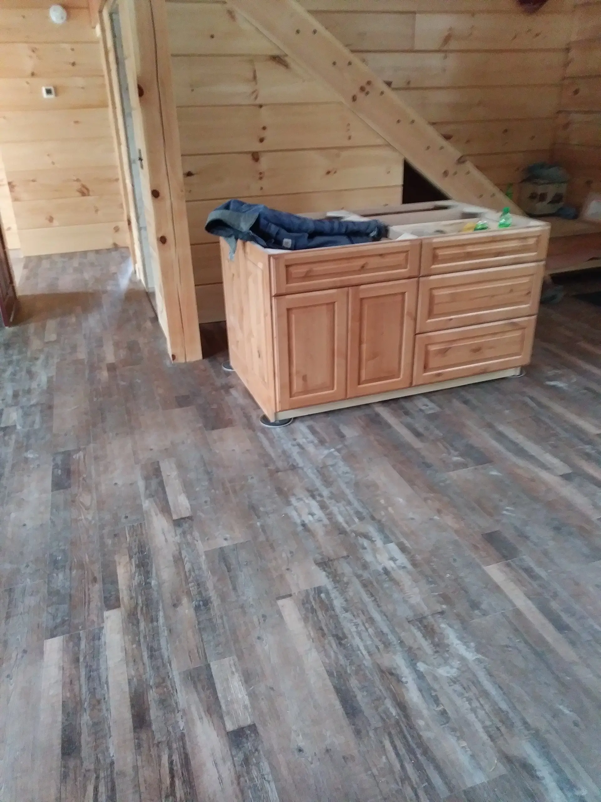 Distressed gray vinyl plank being installed around a kitchen island