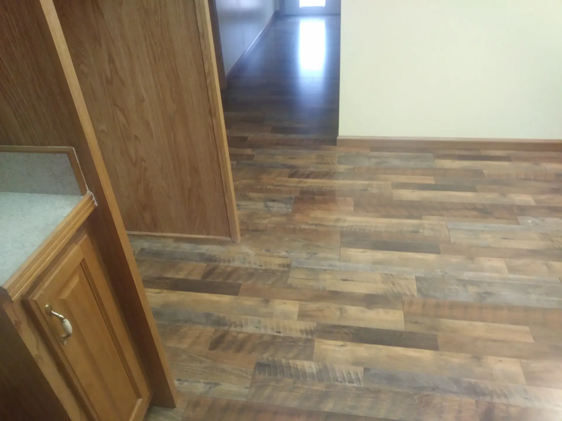 Reclaimed wood look laminate running from kitchen to hallway