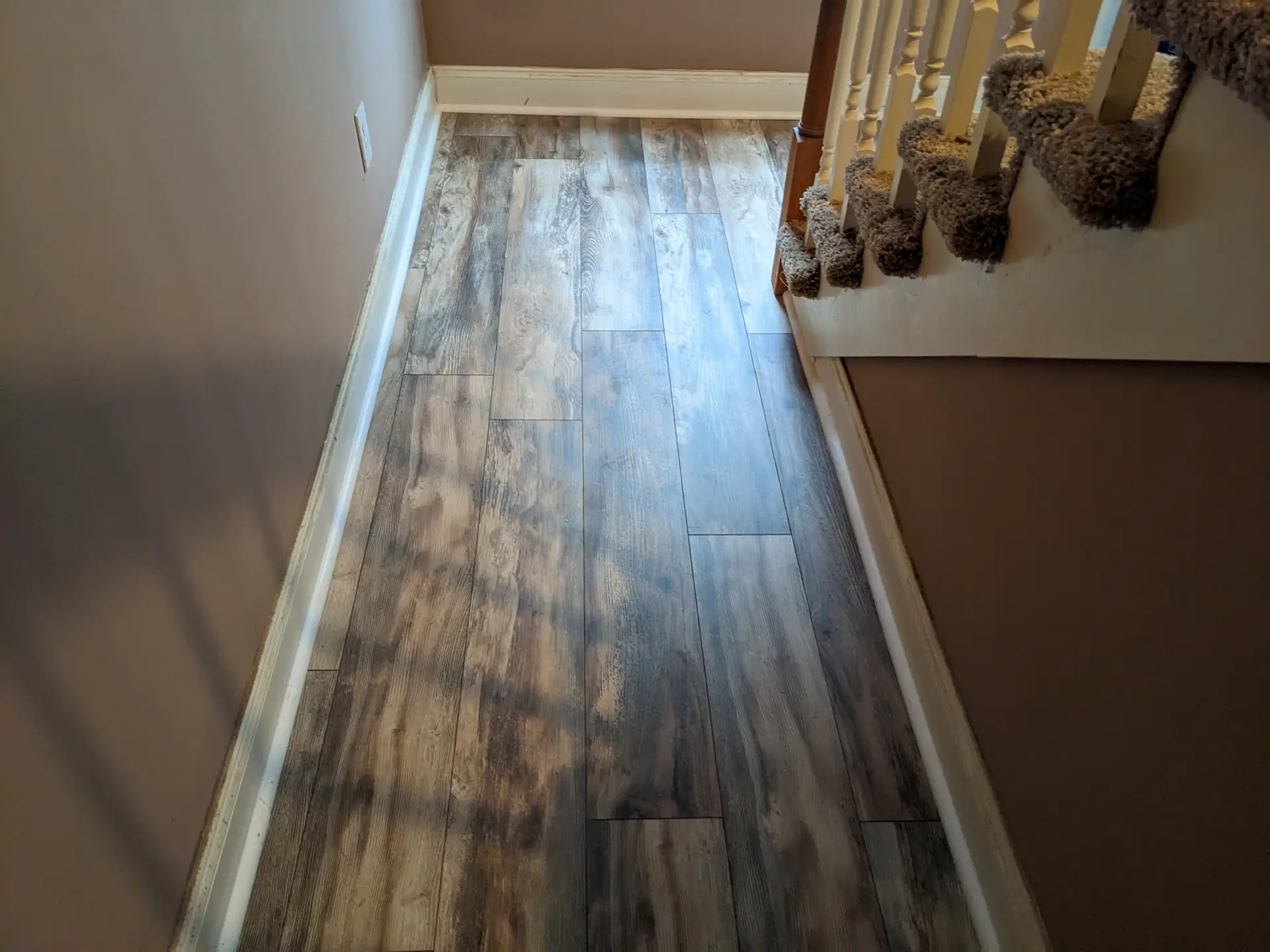 Rustic multi-tone plank flooring installed on a staircase landing